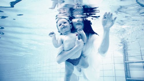 Babysvømming der mor og et barn dykker under vann